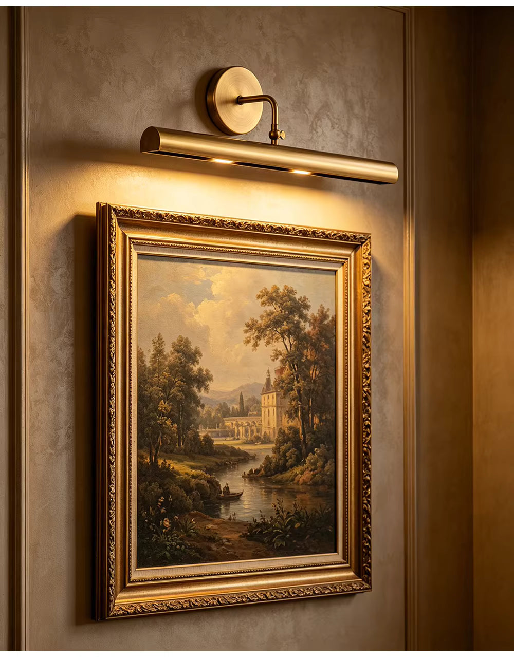 A framed landscape painting hangs on a textured beige wall beneath a modern adjustable wall sconce. The ornate gold frame surrounds a classical scene with trees, water, and a building, and the warm light from the sconce casts a soft glow over the artwork.