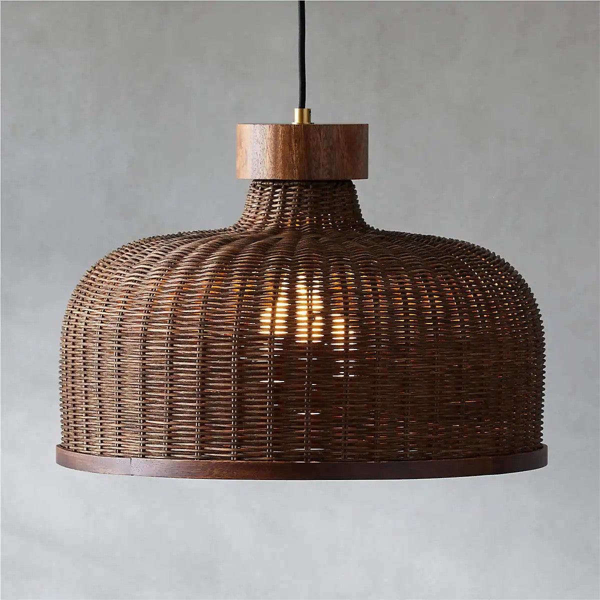 Espresso wicker bell pendant shade throwing a warm internal glow through tightly woven sustainable rattan fibers.