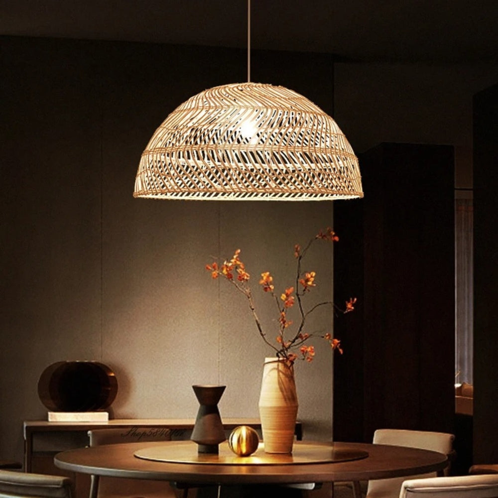 Modern wicker chandelier set of three casting warm ambient light over elegant wine glasses on a dining table.