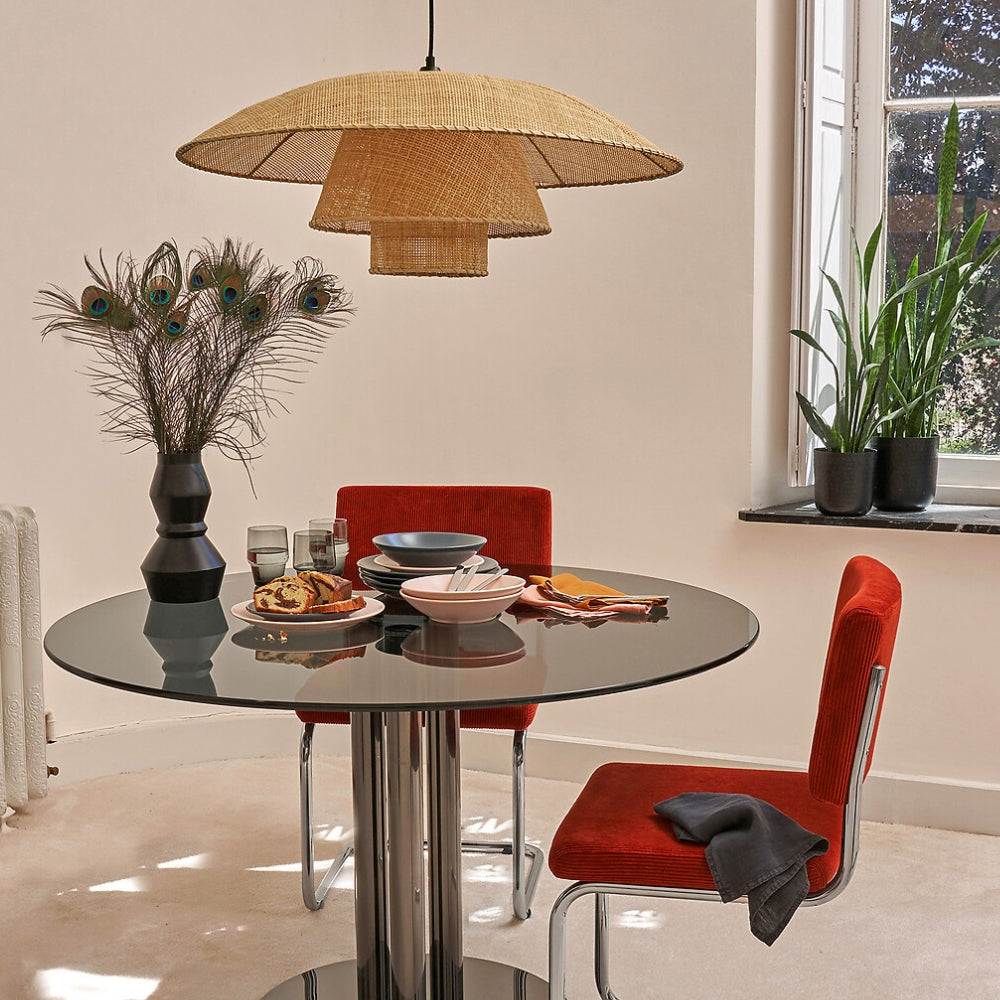 Elegant wide brim kitchen island light in a soft natural straw tone, casting warm ambient glare-free illumination over a wooden dining set.