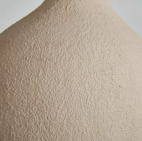 Neutral tone ceramic bell pendant light fixtures with different shapes hanging together in a minimalist room.
