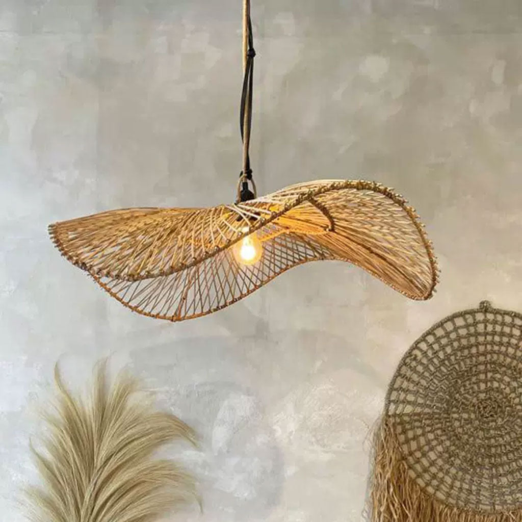 Large open-weave straw sun hat chandelier displaying a fluid, undulating silhouette that filters a warm interior glow.