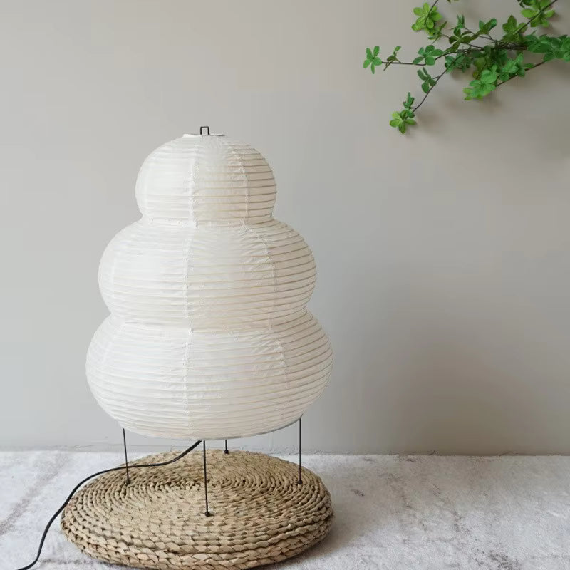 White paper lantern-style lamp with a woven base on a light surface.