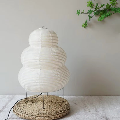 White paper lantern-style lamp with a woven base on a light surface.