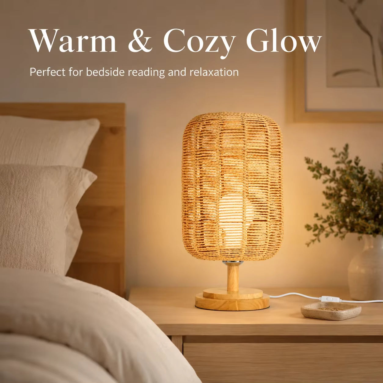 A warm, glowing woven rattan table lamp with a light wood base on a bedside table in a cozy bedroom setting. White text at the top reads 'Warm & Cozy Glow' and 'Perfect for bedside reading and relaxation'.