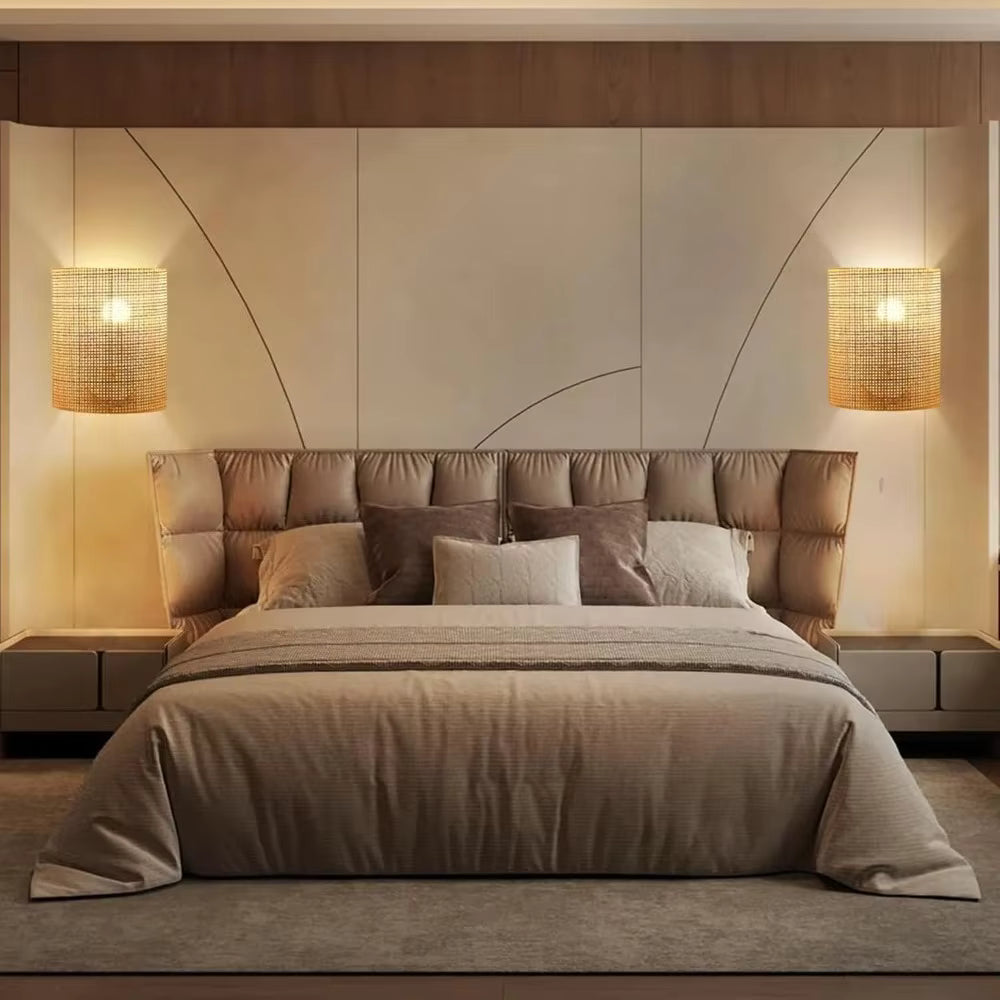Neatly made bed with pillows in a bedroom setting with wall lights.