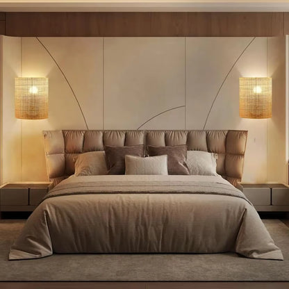 Neatly made bed with pillows in a bedroom setting with wall lights.