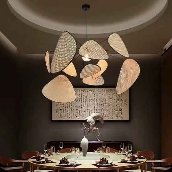 Modern statement wicker hanging light with multi-panel rattan mesh shades creating artistic shadows on a white background.