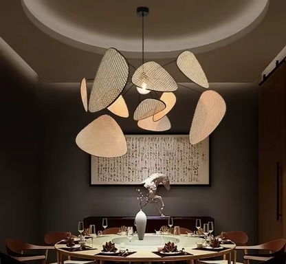 Modern statement wicker hanging light with multi-panel rattan mesh shades creating artistic shadows on a white background.