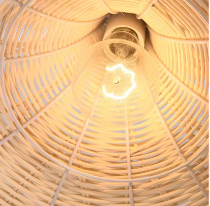 Warmly lit rattan lamp suspended over a wooden table in a dining area.