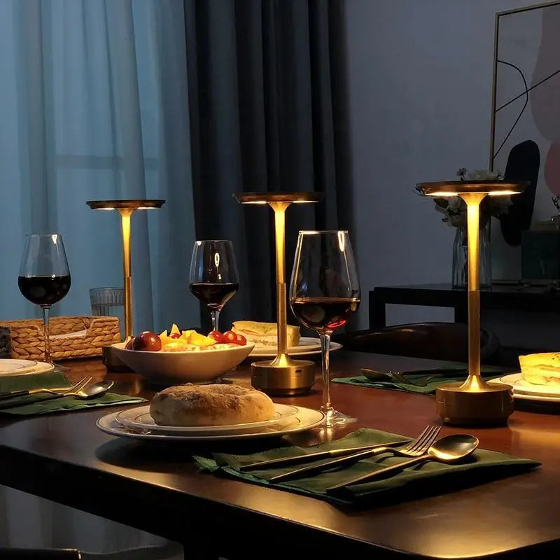 Dining table set with wine glasses, food, and candle holders in a dimly lit room.