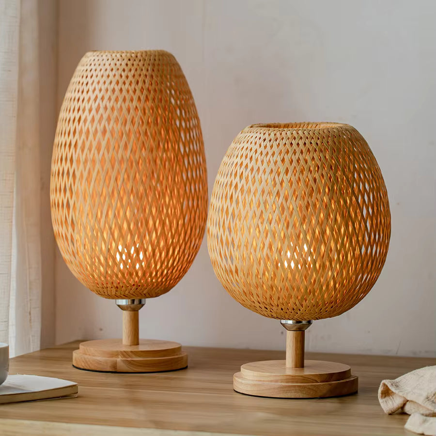 Two woven wooden table lamps on a wooden surface with a neutral background