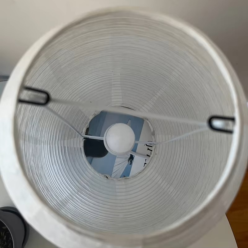 Top-down view of a white paper lantern lampshade with a visible white bulb inside.