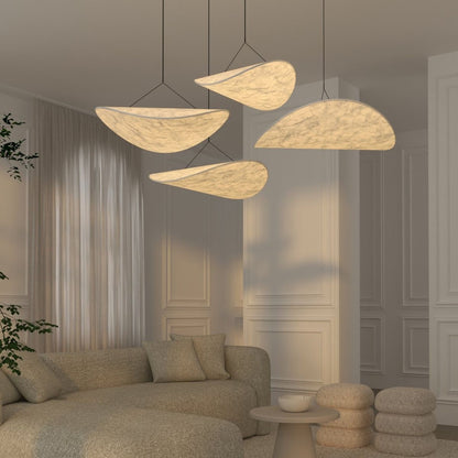 Three modern wabi sabi pendant light fixtures with organic, cloud-like shapes and textured cream-colored shades hang over a beige textured sofa in a minimalist, elegant living room.