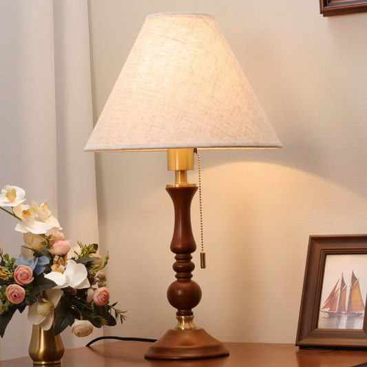 Classic wooden table lamp with a fabric shade and brass pull chain, providing warm, clean illumination for a Scandinavian living room.