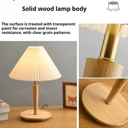 Solid wood table lamp with a pleated cream shade, light natural wood stem and base, and a gold-toned metal neck, shown on a desk with close-up detail views and explanatory text about the transparent-painted wood finish.